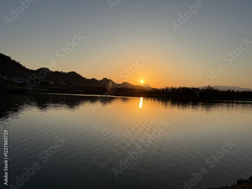 Golden Sunset Over a Serene River with Distant Mountains