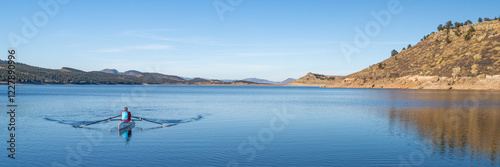 Lonely rower in a coastal rowing shell - Carter Lake in fall or winter scenery in northern Colorado.
