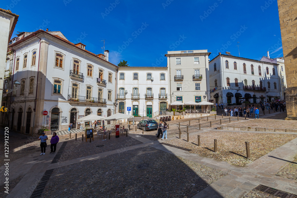 Naklejka premium A historic clock tower with a golden clock face stands atop a traditional building with a red-tiled roof against a blue sky with wispy clouds.