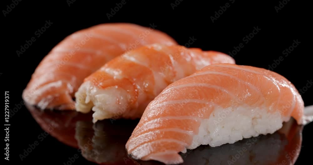 beautiful Japanese meal, fresh salmon and shrimp nigiri sushi with soft rice on a moving plate in front of black background beautiful Japanese meal, fresh salmon and shrimp nigiri sushi with soft rice on a moving plate in front of black background