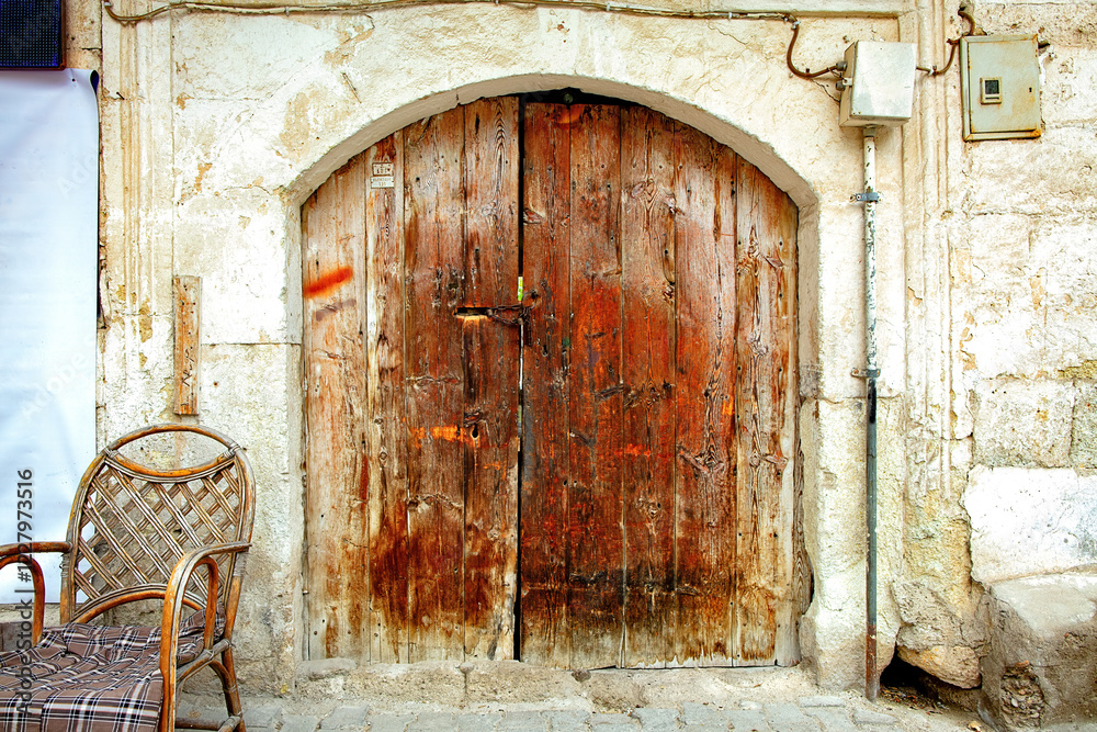 Weathered wooden door adding charm to an ancient stone wall beside a rustic chair