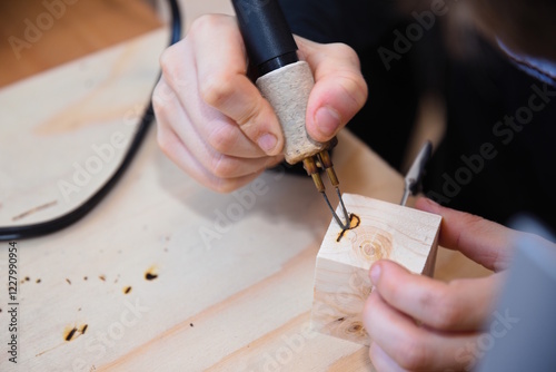 Person mit Brandmalkolben verziert Holzwürfel
