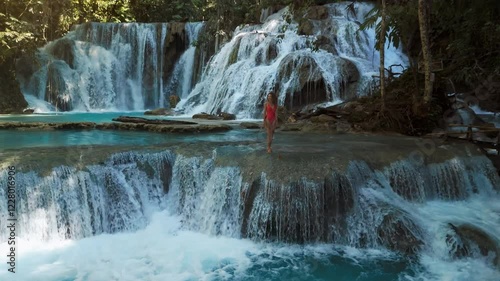 Beauty woman on cascade waterfalls in Indonesia. Scenic waterfall in Luwuk, Sulawesi photo