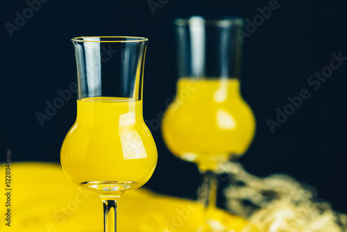 Two stemmed glasses with yellow liquor on a dark background photo