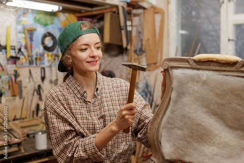 woman restores old wooden chair, works with hammer, concept of repair and restoration of old furniture. Copy space