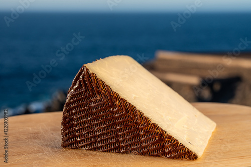 Assortment of Spanish hard cheeses, curado, manchego, goat cheese served outdoor with blue sea on background, close up photo