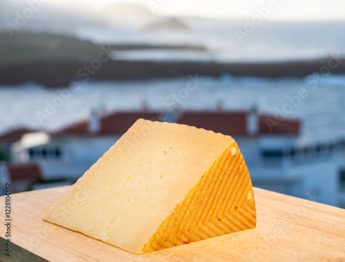 Spanish hard cheese, curado, manchego, goat cheese served outdoor with blue sea on background, close up photo