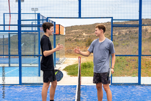 Obraz na płótnie Two young players greeting each other with smiles after a padel match, showcasing sportsmanship and joy on the court. w salonie