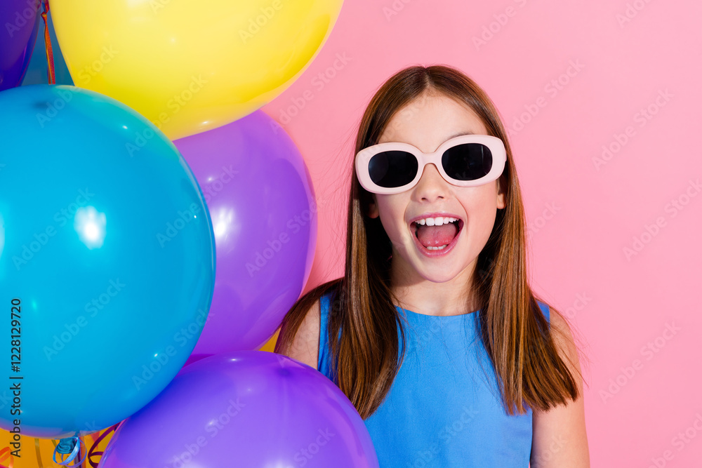 Φωτογραφία Bright young girl wearing sunglasses screaming with joy among colorful balloons