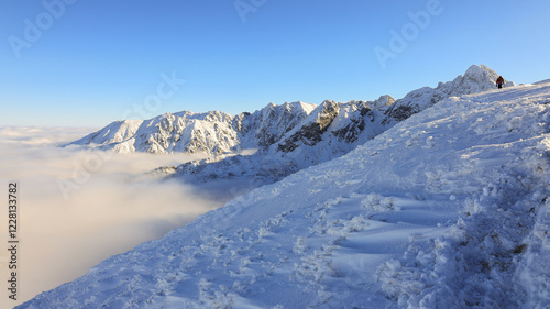 Panorama of the winter peaks of the Tatras from Kasprowy Wierch. A sunny, winter December day. The mountain peaks are covered in thick clouds.
