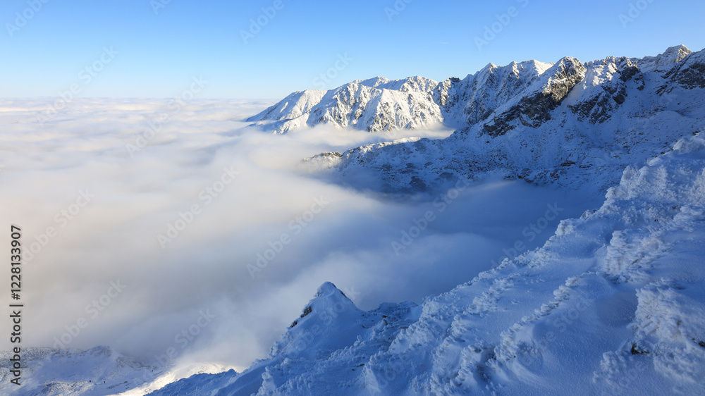 Obraz premium Panorama of the winter peaks of the Tatras from Kasprowy Wierch. A sunny, winter December day. The mountain peaks are covered in thick clouds.