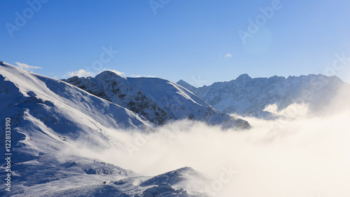 Panorama of the winter peaks of the Tatras from Kasprowy Wierch. A sunny, winter December day. The mountain peaks are covered in thick clouds.