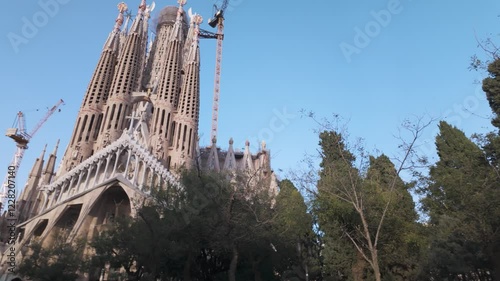 Sagrada Familia cathedral in Barcelona, framed by lush greenery, under a vibrant blue sky. This globally recognized architectural marvel is both a cultural monument and an artistic masterpiece.