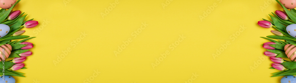 Easter background with colorful eggs and spring flowers on yellow background with copy space, top view Easter background with colorful eggs and spring flowers on yellow background with copy space, top view