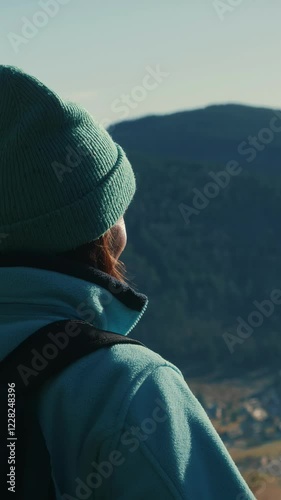 Female tourist with backpack hiking and standing on mountain top. Vertical video