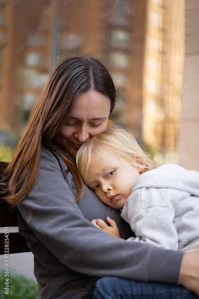 Obraz premium a three-year-old boy rested his head on his mother's shoulder, motherhood