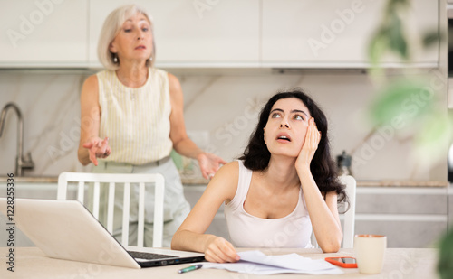 Adult woman is quarreling with her mother for documents of household at home. photo