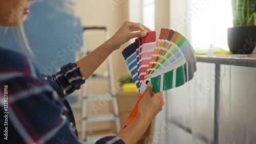 Фотография Woman choosing paint colors in modern, bright living room, showcasing creative home decor with vibrant swatches, stylishly reflecting interior design trends for apartment renovation