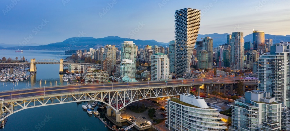 Obraz premium Vancouver skyline at dawn, featuring the iconic Granville Bridge, modern high-rises, and a vibrant harbor. Urban cityscape. Vancouver, British Columbia, Canada