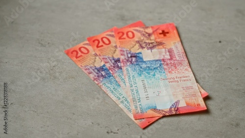 Swiss banknotes in denominations of twenty francs are arranged on a concrete surface, highlighting switzerland's vibrant currency design. photo