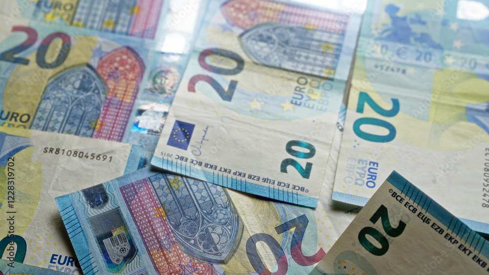 Euro banknotes scattered on a surface showcasing various twenty euros bills from the european union with detailed designs and holograms. Euro banknotes scattered on a surface showcasing various twenty euros bills from the european union with detailed designs and holograms.