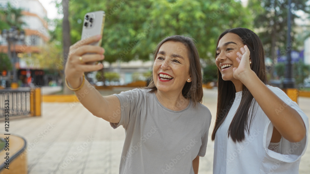 Women enjoying a video call in an urban park, sharing smiles and laughter, embodying the essence of family connection and friendship outdoors. Women enjoying a video call in an urban park, sharing smiles and laughter, embodying the essence of family connection and friendship outdoors.