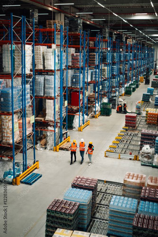 Fototapeta premium Warehouse workers walking and controlling inventory in large distribution center