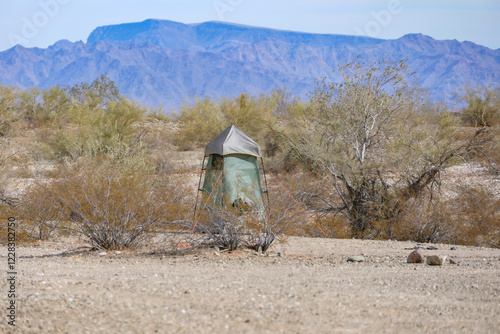 Tent shower and toilet enclosure sitting alone in the desert