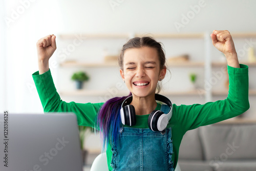 Yes, I Did It. Emotional Girl Shaking Clenched Fists With Closed Eyes Celebrating Success Sitting At Desk With Pc At Home. Positive Emotion And Expression, Good Test Result. Joy Of Victory Concept photo