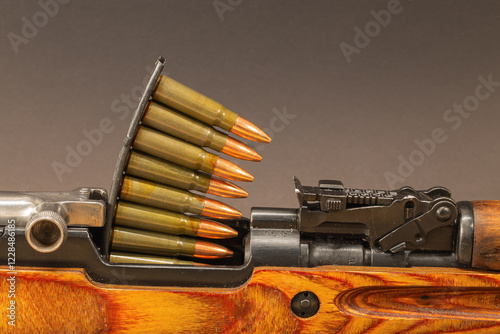 A close-up view of a classic semi-automatic rifle with a stripper clip loaded with rifle cartridges. Russian SKS.