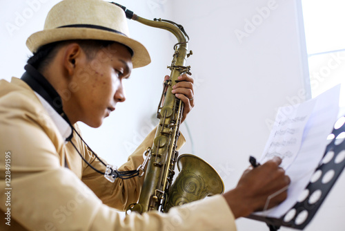 Photography Side View Of Young Male Musician With Saxophone Writing On Music Sheet