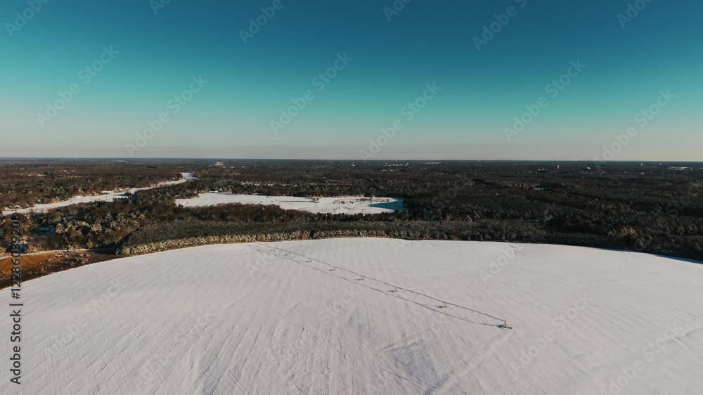 An aerial drone view showcasing a snow-covered pivot irrigation system in a vast field with a treeline backdrop, captured in South Georgia's rare snowfall. An aerial drone view showcasing a snow-covered pivot irrigation system in a vast field with a treeline backdrop, captured in South Georgia's rare snowfall.
