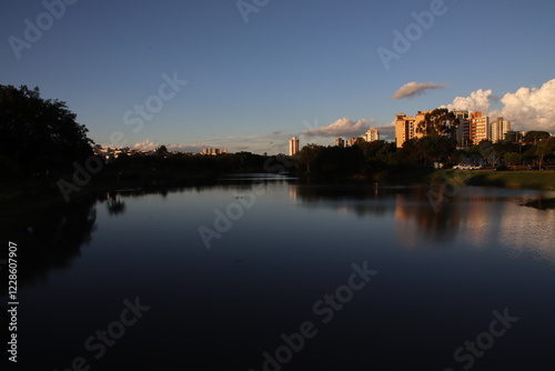 View of a late afternoon at the Indaiatuba Ecological Park, a city in the countryside of the state of São Paulo - Brazil. Gradient sky, shade of trees and reflection of buildings in the lake water
