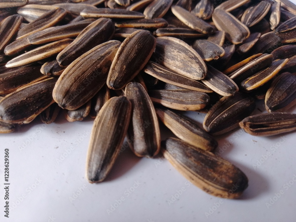 Kuaci or kwatji sunflower seeds. Scattered on a wooden table. Snack on dried and salted sunflower seeds. Selective focus Kuaci or kwatji sunflower seeds. Scattered on a wooden table. Snack on dried and salted sunflower seeds. Selective focus