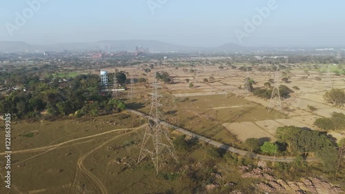 Aerial view of farmland and power lines, High voltage transmission tower landscape, Drone footage of rural fields, Countryside with electric towers, Scenic drone shot of power grid, Agricultural lands photo