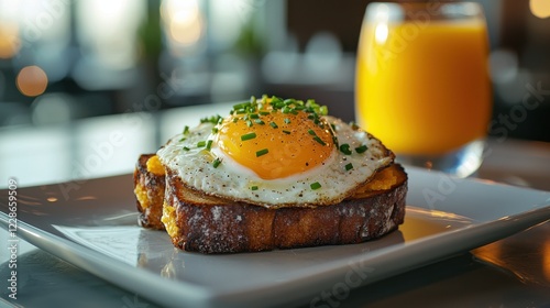 A delightful breakfast dish featuring a golden yolk egg on toasted bread, garnished with chives, served alongside a refreshing glass of orange juice. photo