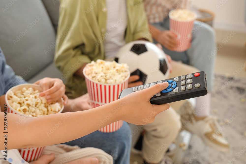 Happy family with TV remote control, popcorn and soccer ball watching football game at home, closeup Happy family with TV remote control, popcorn and soccer ball watching football game at home, closeup