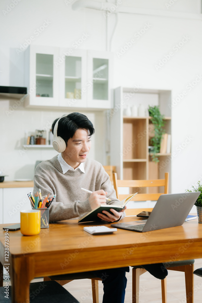 Young man using laptop while sitting at home. Young woman sitting in kitchen and working Young man using laptop while sitting at home. Young woman sitting in kitchen and working