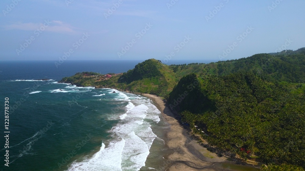 Aerial drone view of coastline with hills and trees, as well as view of coral cliffs and sea with waves from the ocean in Pecaron Beach Kebumen Central Java Indonesia Aerial drone view of coastline with hills and trees, as well as view of coral cliffs and sea with waves from the ocean in Pecaron Beach Kebumen Central Java Indonesia