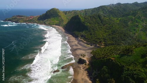 Aerial drone view of coastline with hills and trees, as well as view of coral cliffs and sea with waves from the ocean in Pecaron Beach Kebumen Central Java Indonesia photo