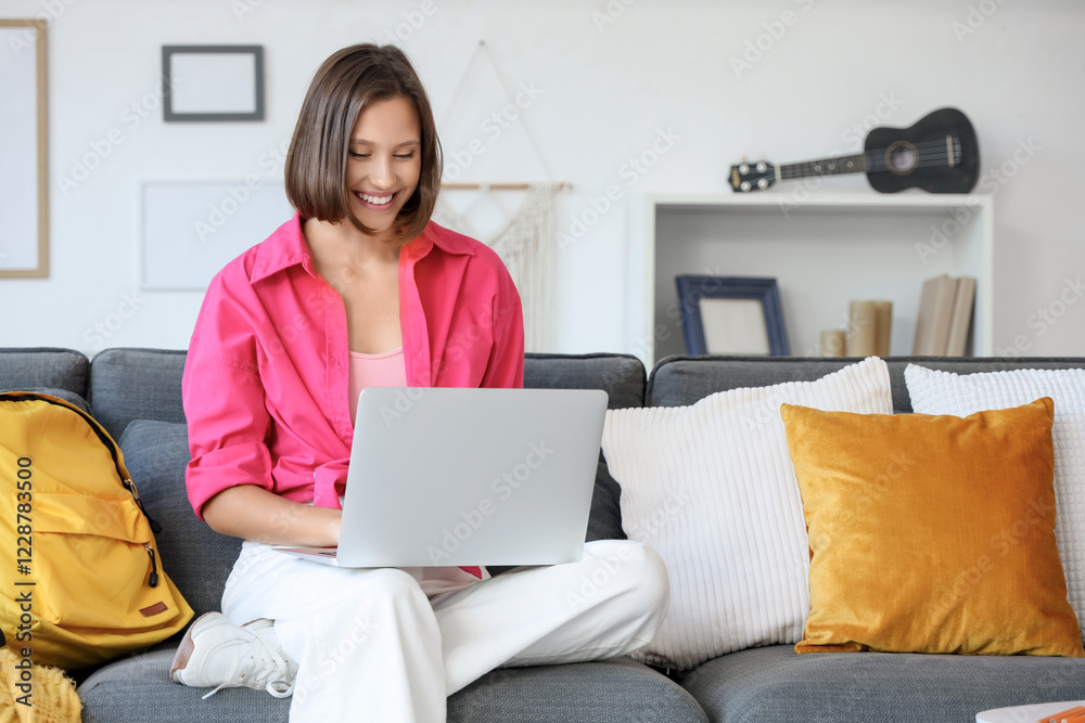 © Pixel-Shot - Teenage girl with laptop filling out online college application form on sofa at home