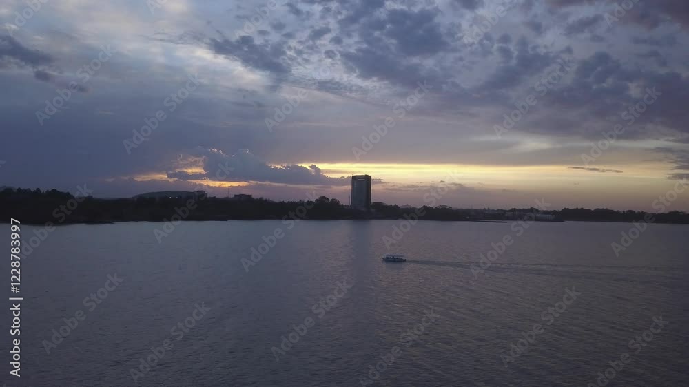 A boat is sailing on a lake during sun set. A boat is sailing on a lake during sun set.
