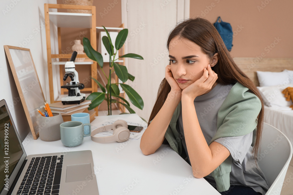 Tired female student studying at table in room Tired female student studying at table in room
