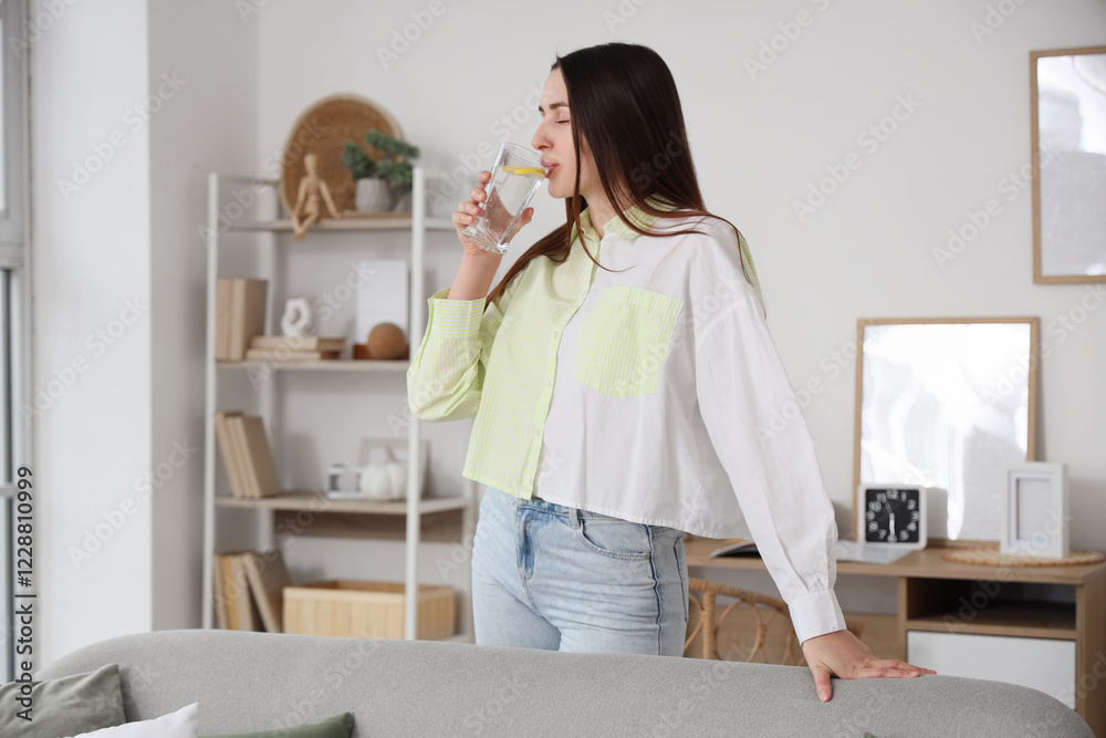 Beautiful young woman drinking lemon infused water at home Beautiful young woman drinking lemon infused water at home