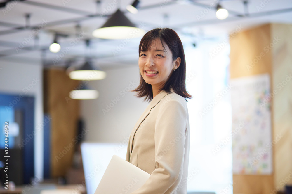 オフィスでノートパソコンを抱える笑顔の日本人女性のポートレート