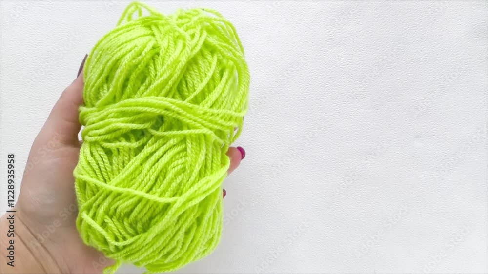 A woman's hand holds a green ball of knitting thread. Green wool yarn. Knitting. 
