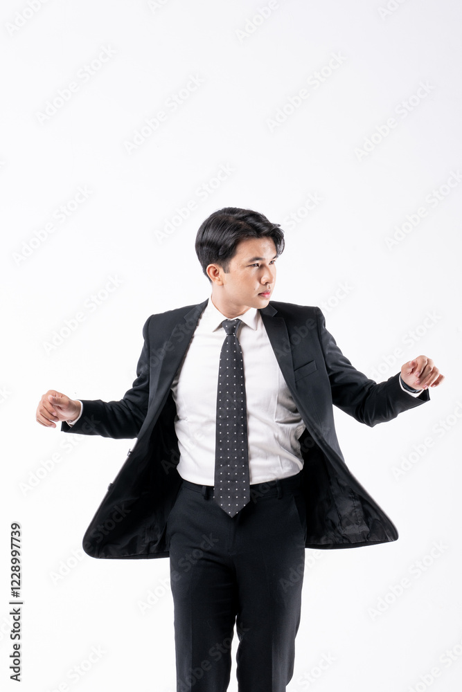 A man in a black suit and tie stands in front of a white background A man in a black suit and tie stands in front of a white background