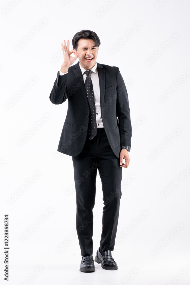 A man in a black suit and tie stands in front of a white background A man in a black suit and tie stands in front of a white background