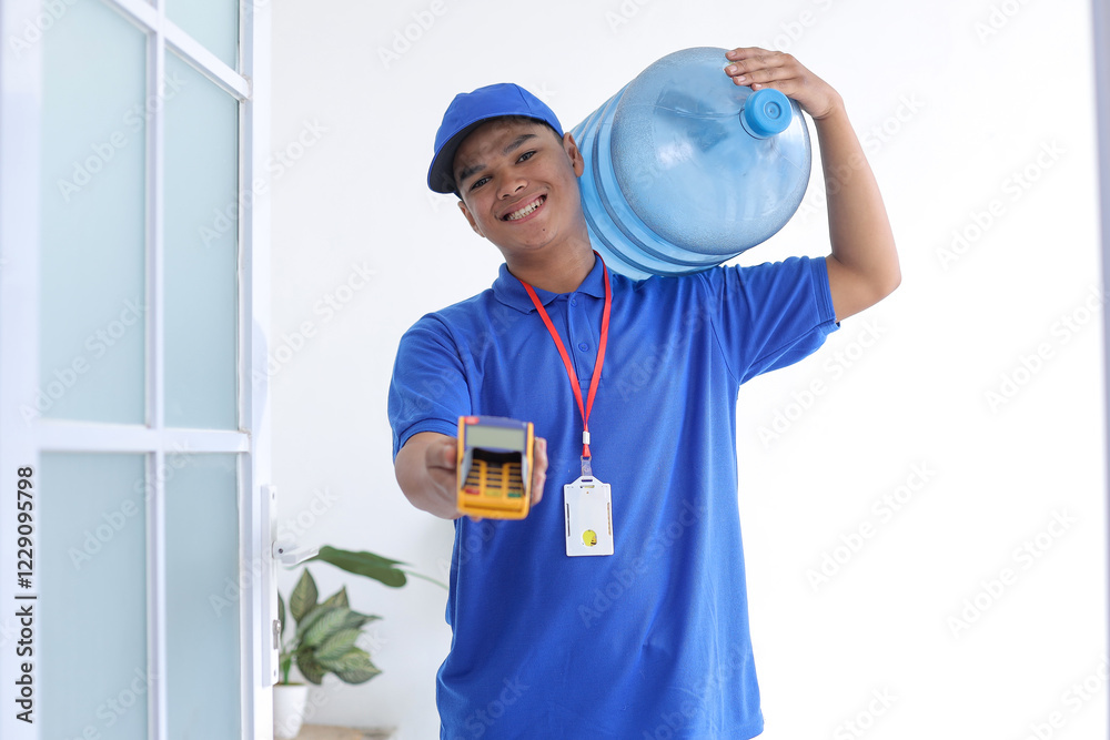 Young Deliveryman Carrying Water Galloon And Giving EDC Machine In Front Of The Door. Home Service And Cashless Payment Concept. Young Deliveryman Carrying Water Galloon And Giving EDC Machine In Front Of The Door. Home Service And Cashless Payment Concept.