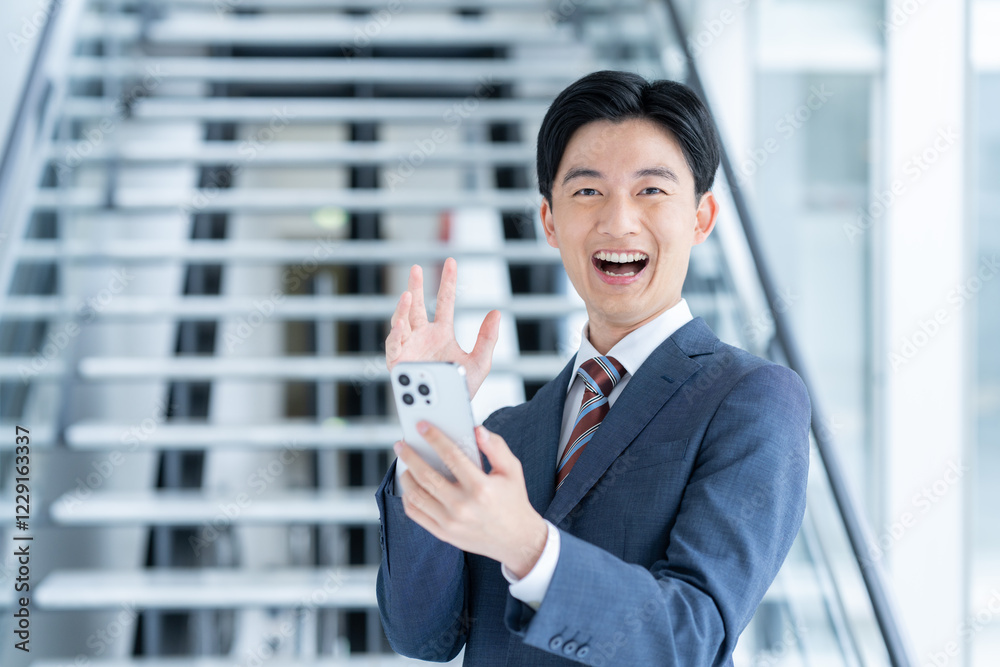 オフィスでスマホを使うビジネスマン オフィスでスマホを使うビジネスマン